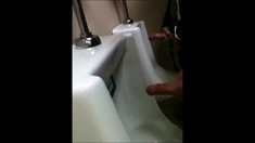 two slim dicks getting wanked at the urinals